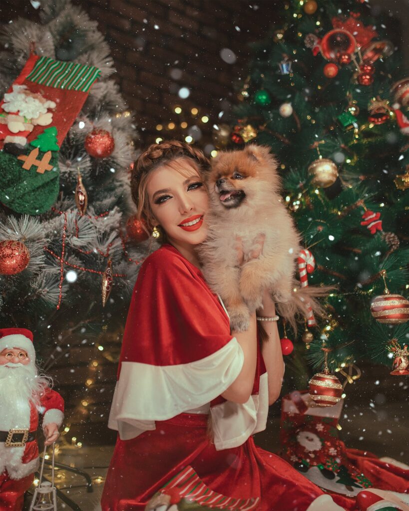 Woman Holding Dog Beside Christmas Tree